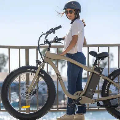 A woman standing beside her Fat Murf electric bike in the colour desert.