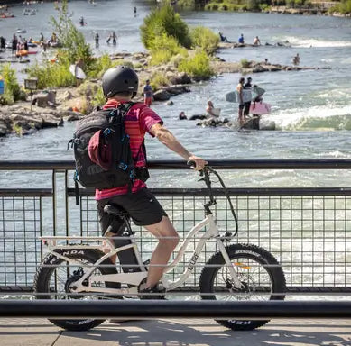 A man stopped on a bridge with his Higgs step through electric bike in desert gloss.