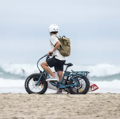 A boy at a beach in Australia on his Higgs step thru electric bike.