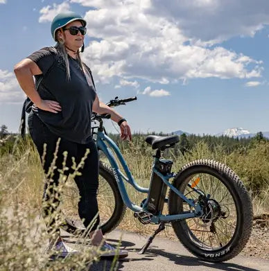 A woman standing beside her fat tyre electric bike on a bike path in Australia.