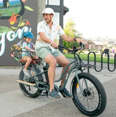 A father and son on an Alpha Murf Cargo e-bike in color Jungle.